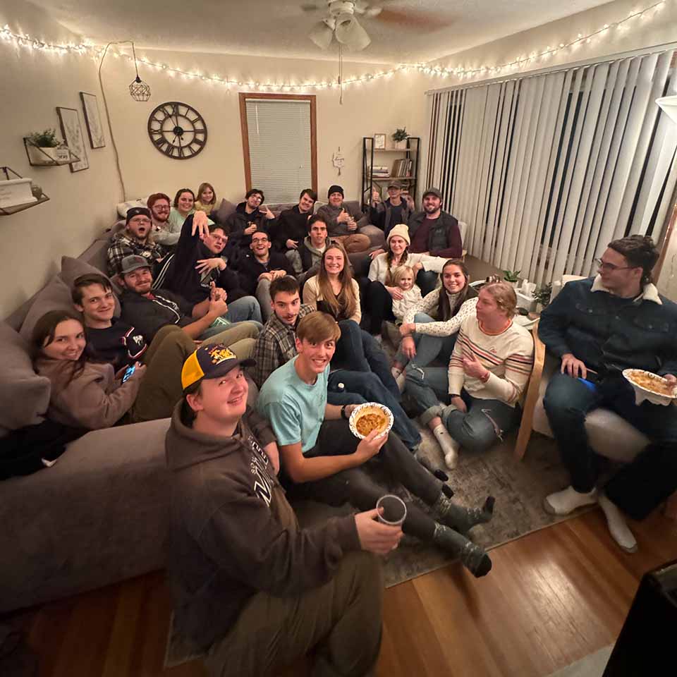 Large group of college students gathered in a living room